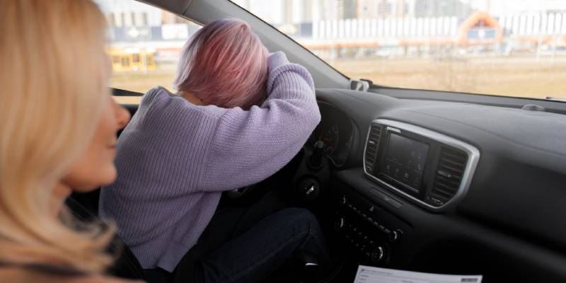 Une conductrice abattue, la tête posée sur le volant, avec une passagère à ses côtés